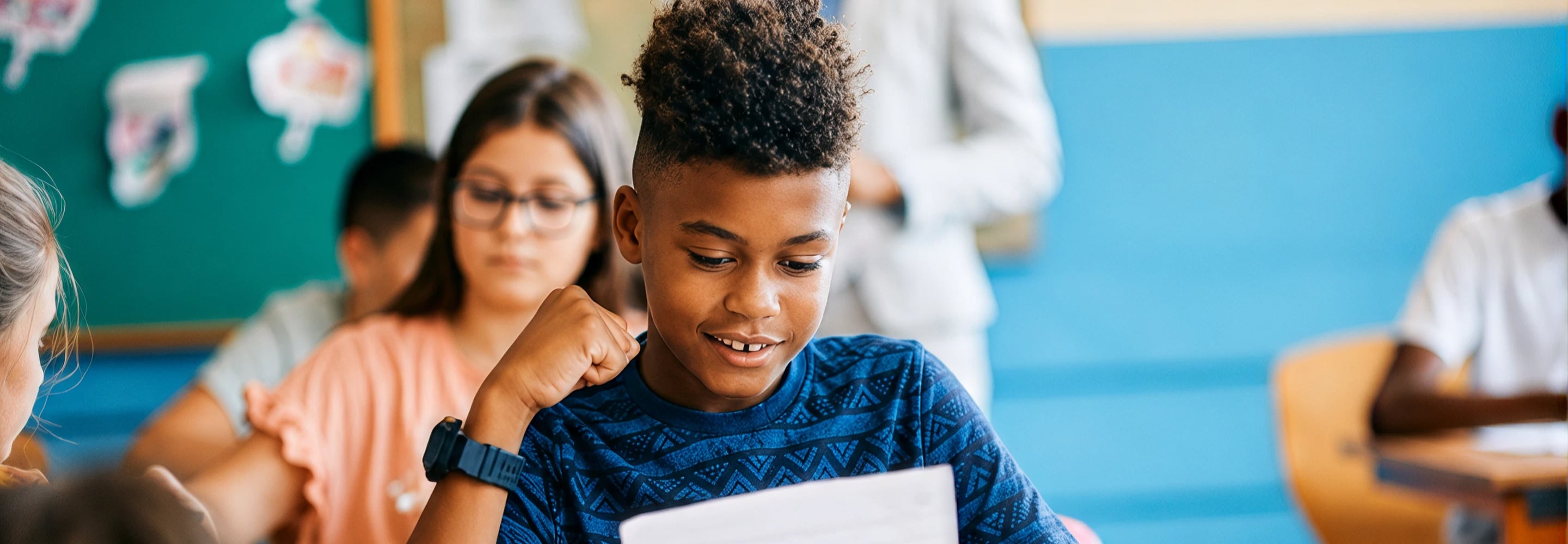 Smiling student celebrating while reviewing his work in a classroom