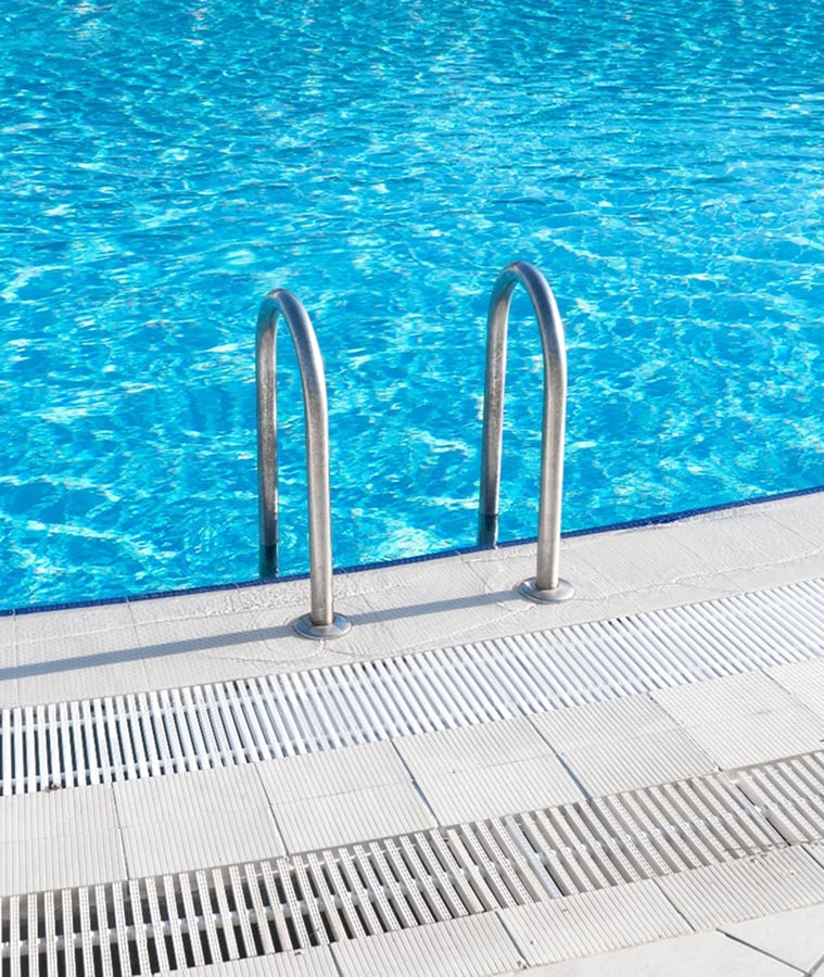 Clean, sparkling residential swimming pool with a stainless steel ladder