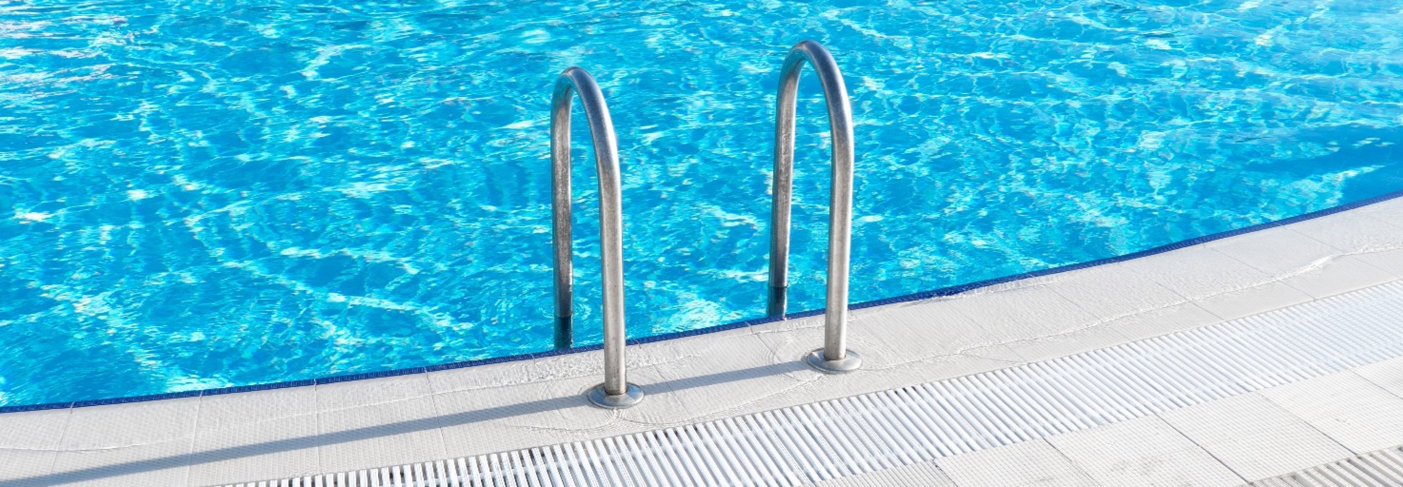 Clean, sparkling residential swimming pool with a stainless steel ladder