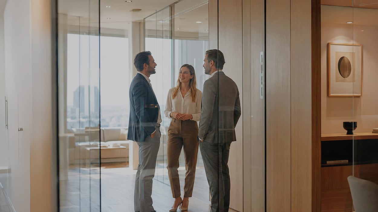 Three colleagues in business attire talking in a bright, modern office