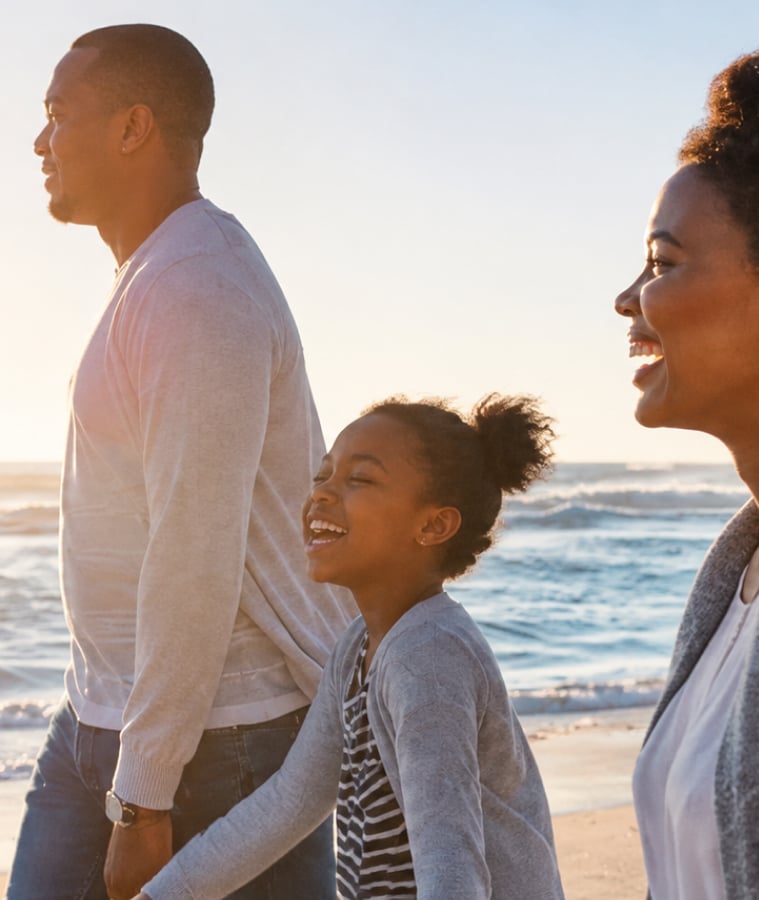 Family walking together on the beach at sunset
