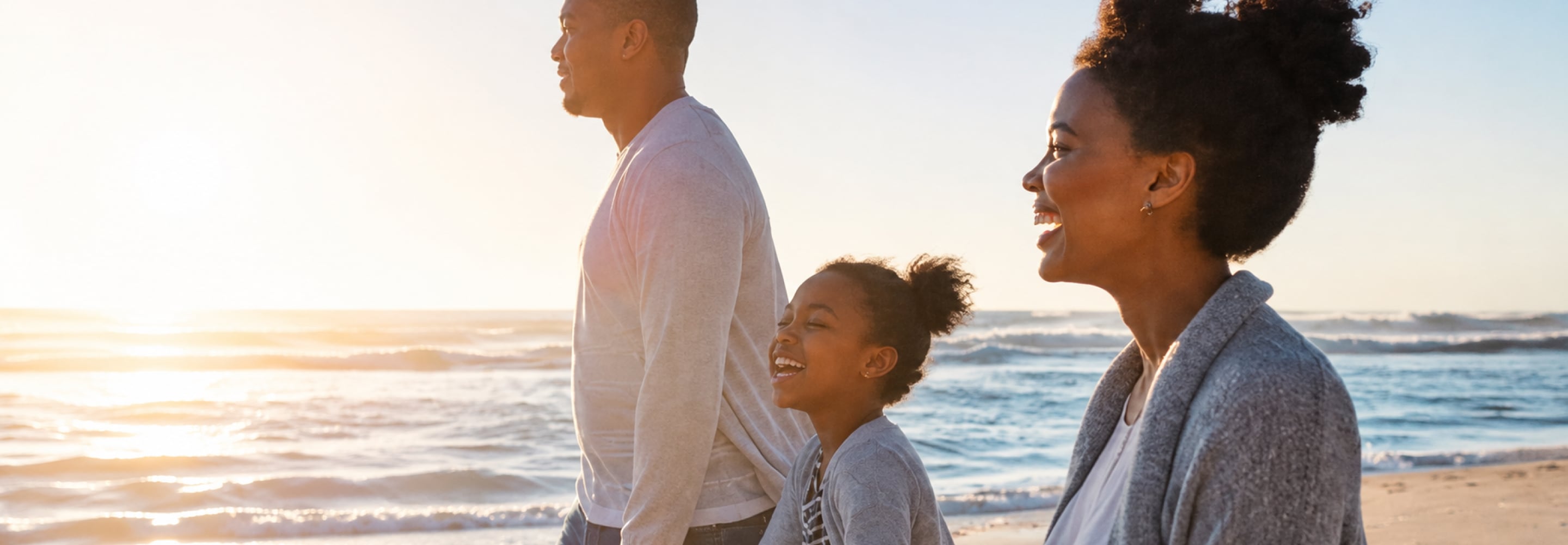 Family walking together on the beach at sunset