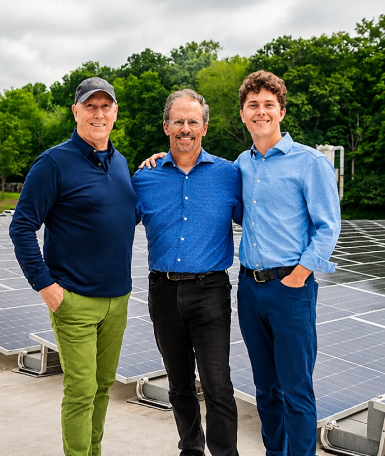 Smiling team members standing in front of rooftop solar panels