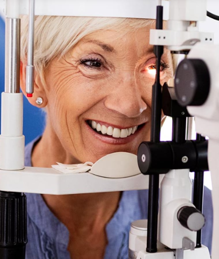 Smiling senior woman having an eye exam at an ophthalmic instrument