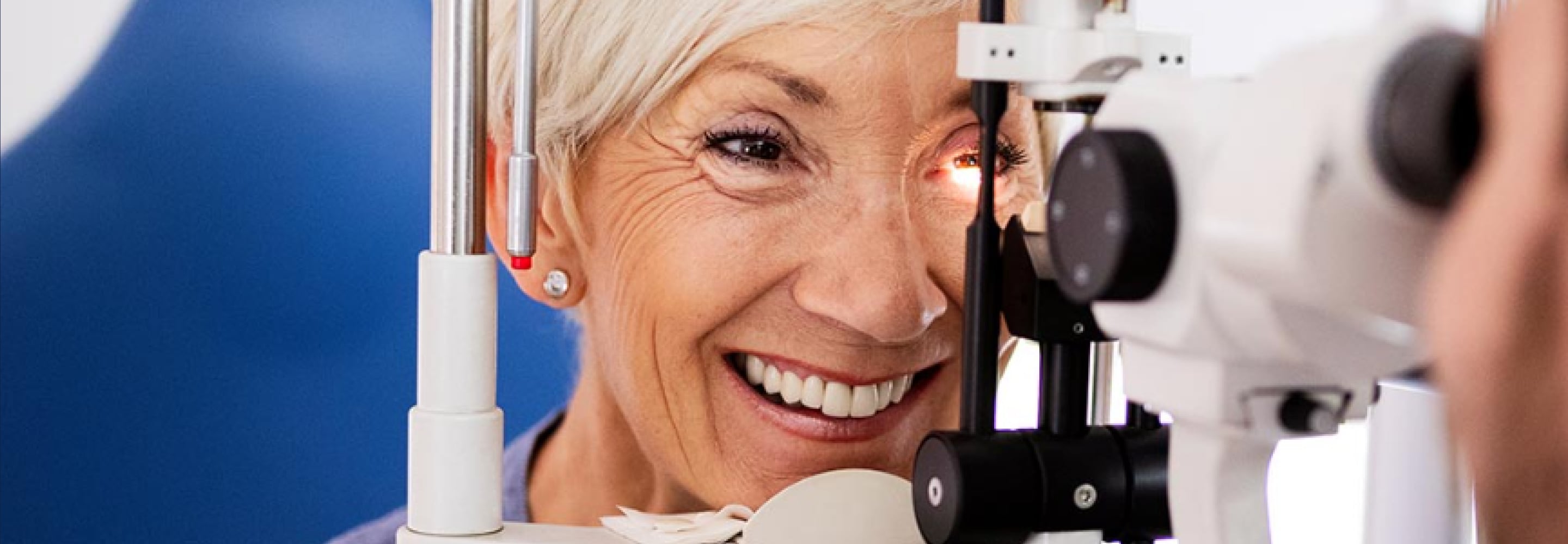 Smiling senior woman having an eye exam at an ophthalmic instrument