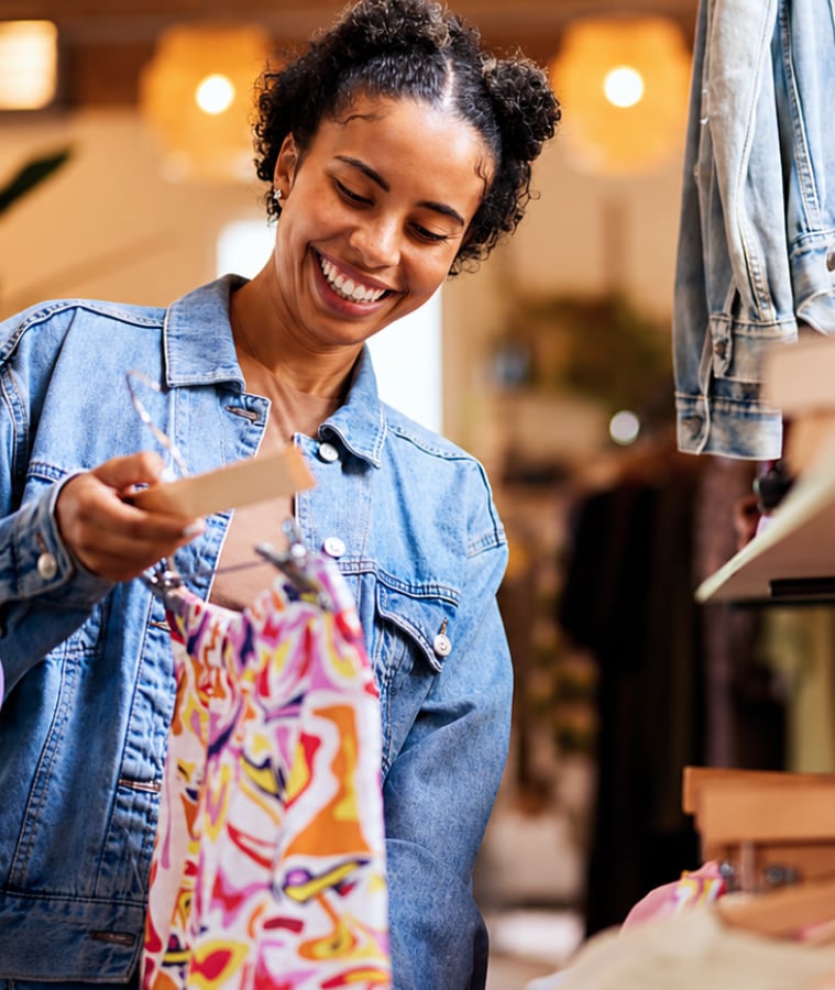 Smiling woman shopping for clothes and checking a price tag in a store