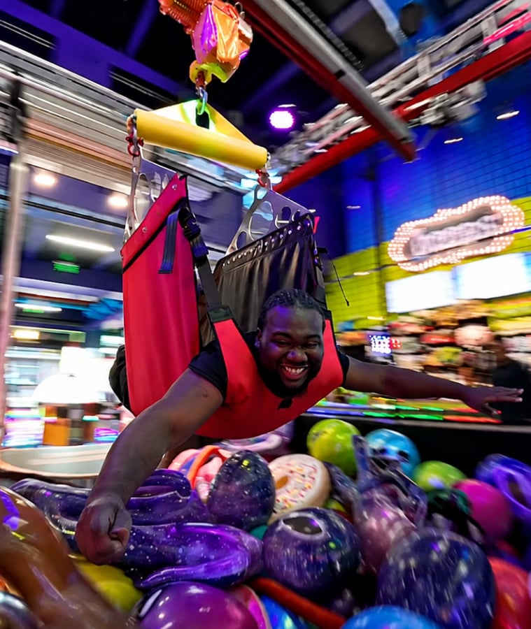 Man laughing while playing a game in a colorful arcade
