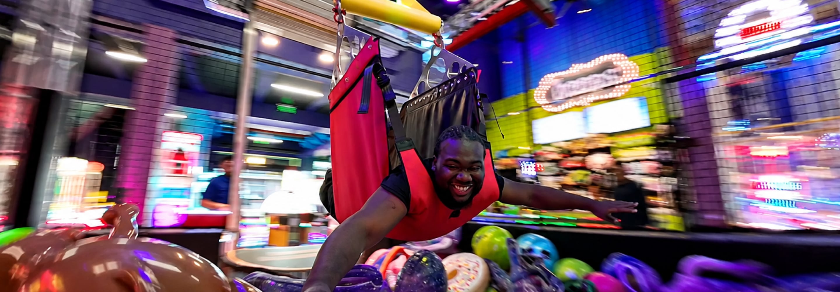 Man laughing while playing a game in a colorful arcade