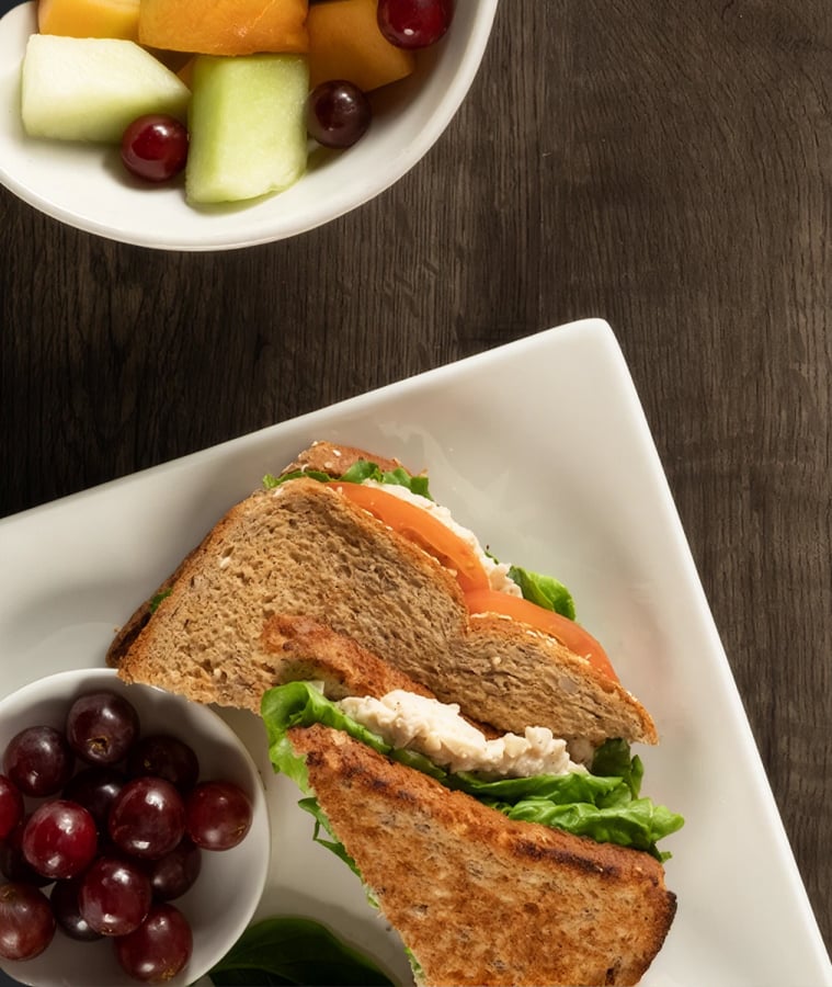 Prepared sandwich next to a snack plate of crackers, cheese, and grapes