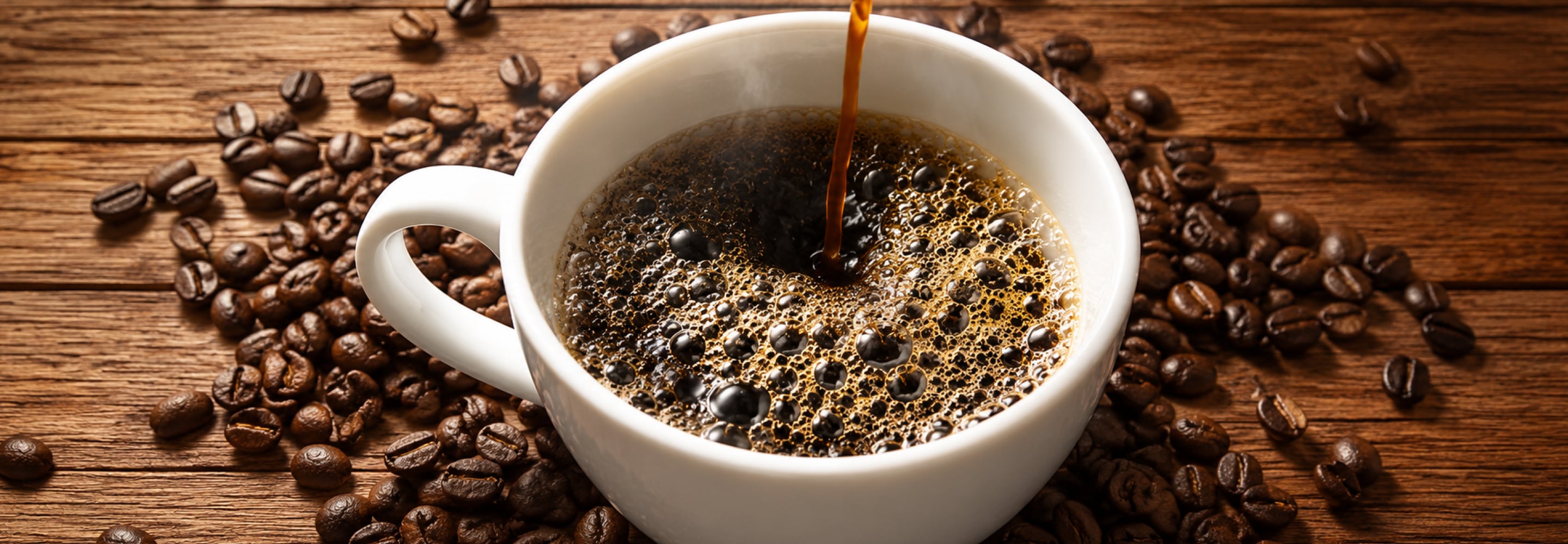 Fresh coffee pouring into a white cup surrounded by roasted coffee beans