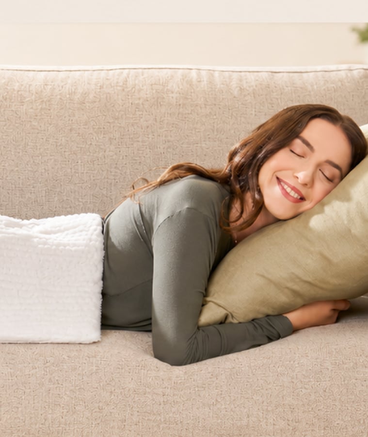 Woman resting on a couch with a pillow, recovering at home