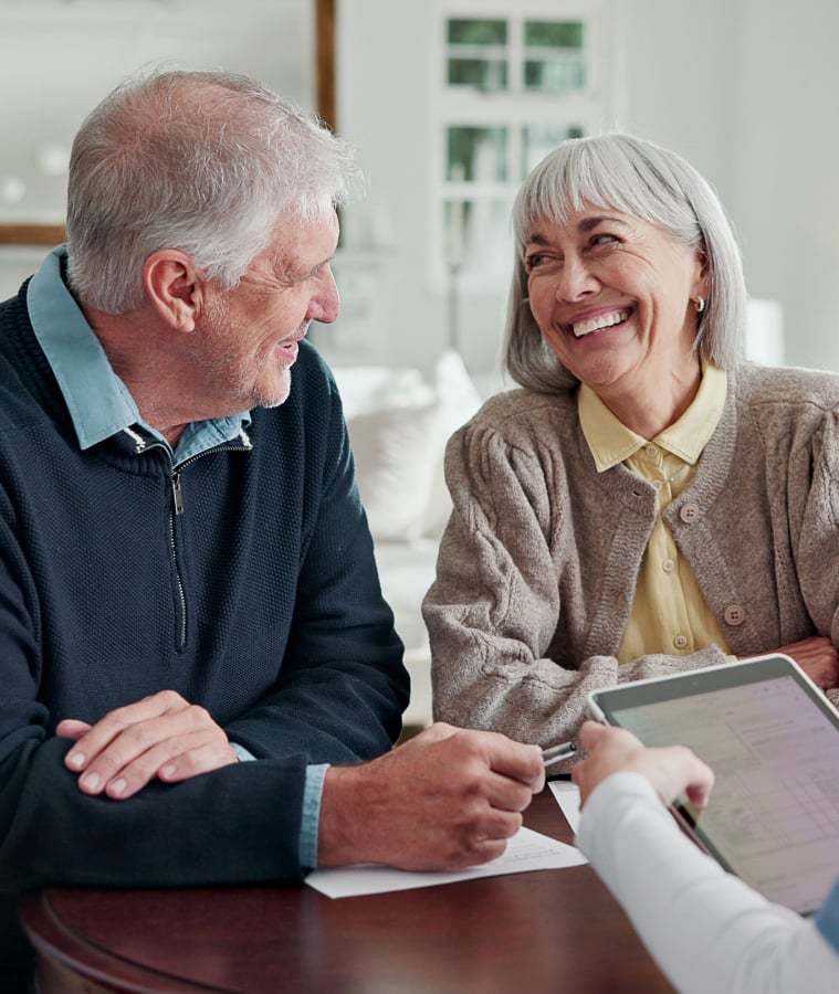 Smiling senior couple talking with a caregiver at home