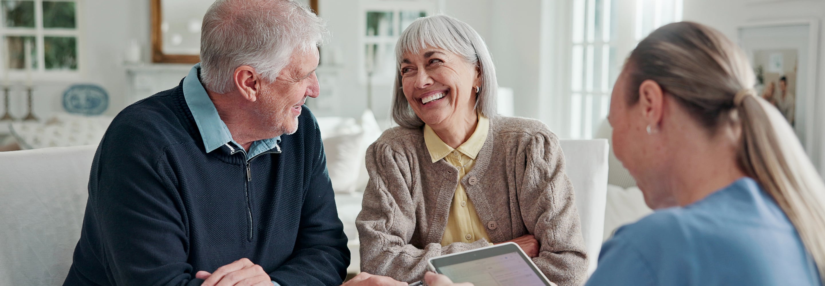 Smiling senior couple talking with a caregiver at home