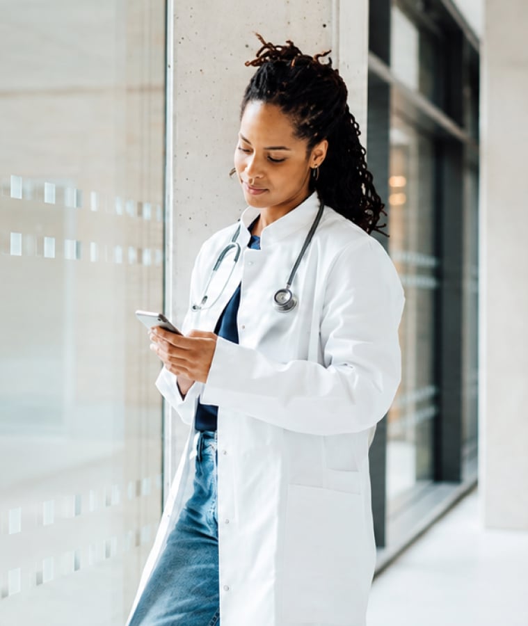 Doctor in a white coat reviewing information on a smartphone