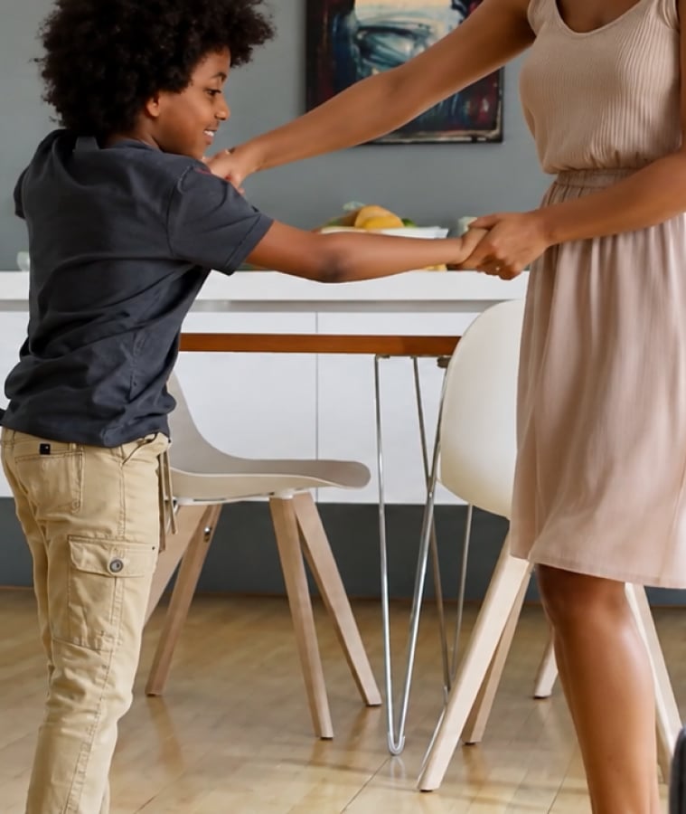 Young boy reaching for food at a kitchen table in a bright, modern home