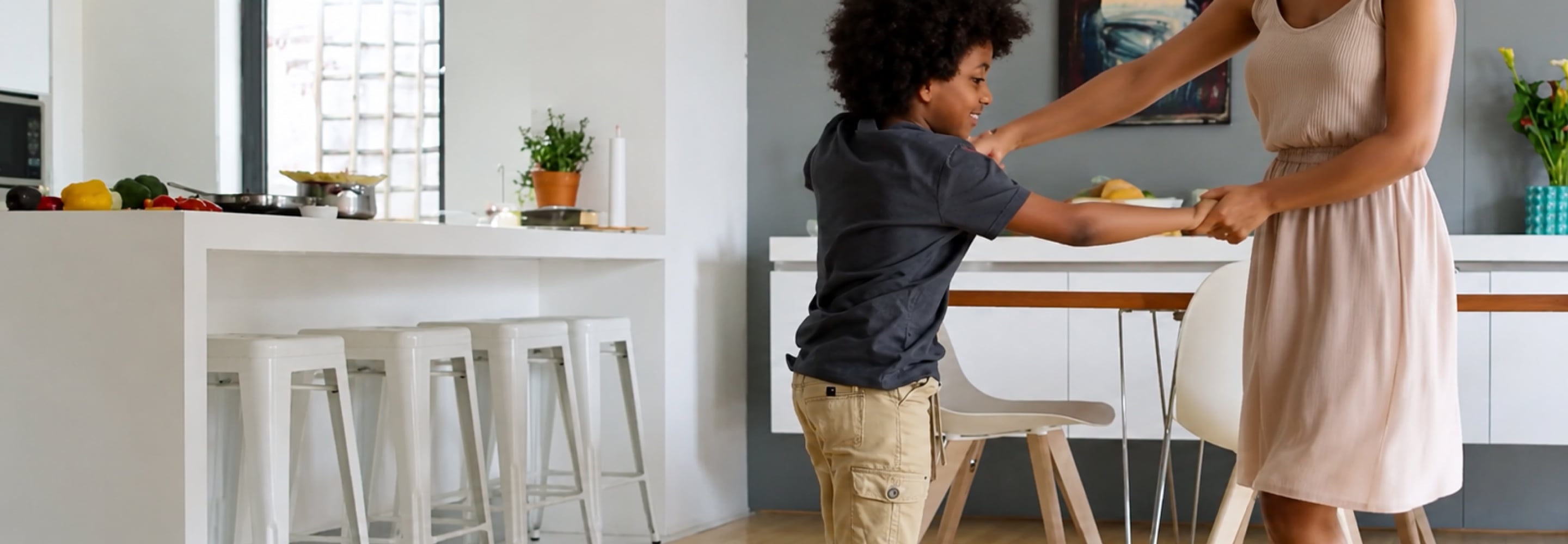 Young boy reaching for food at a kitchen table in a bright, modern home