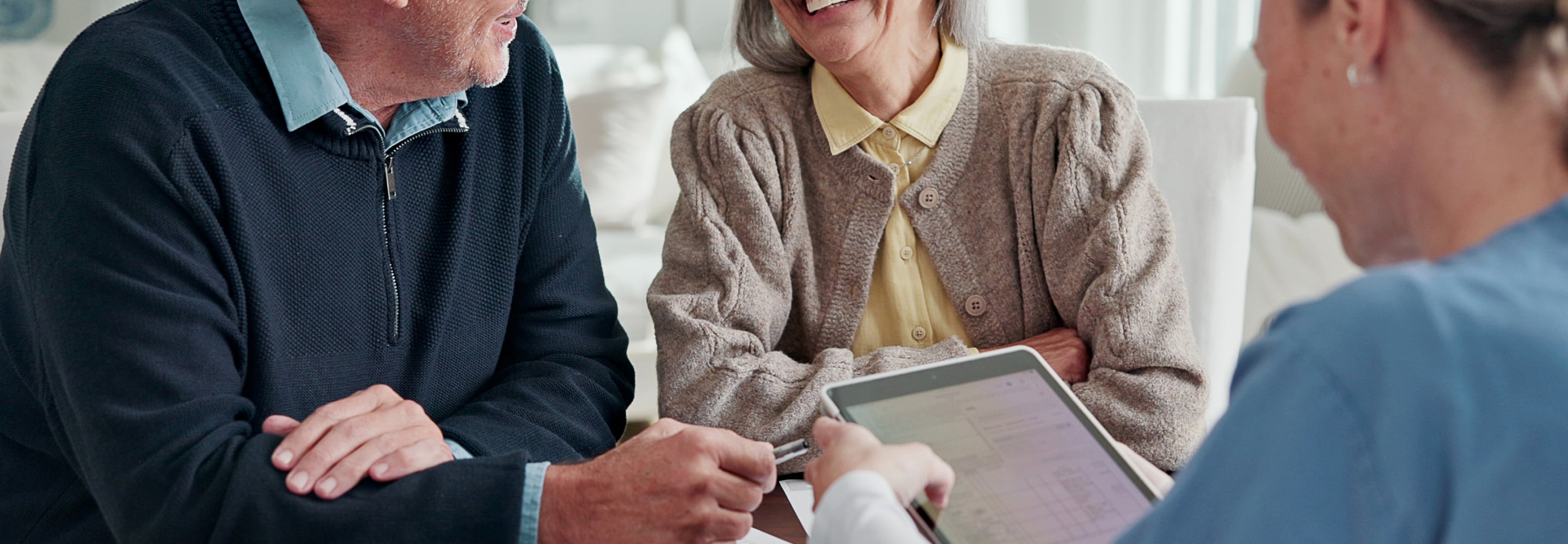Senior couple talking with an advisor who is holding a tablet