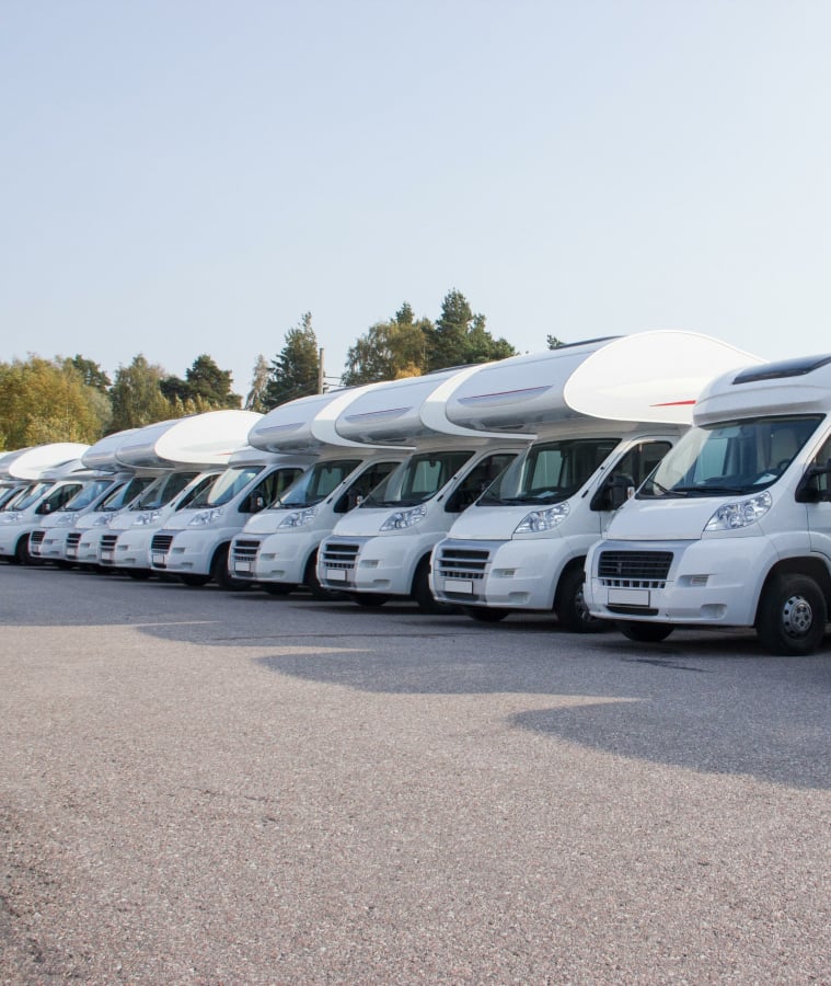 Row of white motorhomes parked in a lot