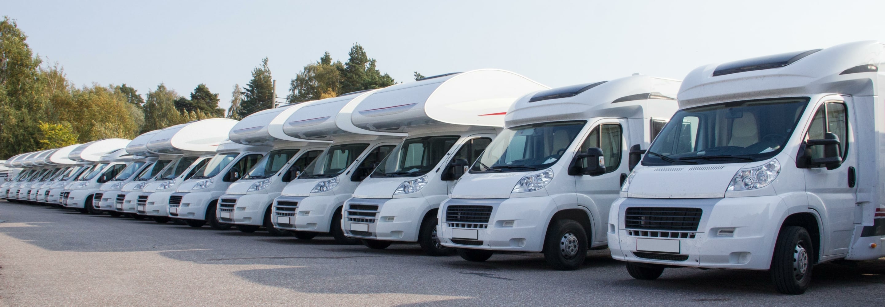 Row of white motorhomes parked in a lot