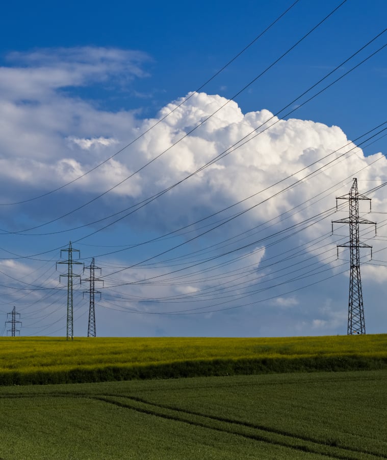 Electricity transmission towers and power lines over a green field