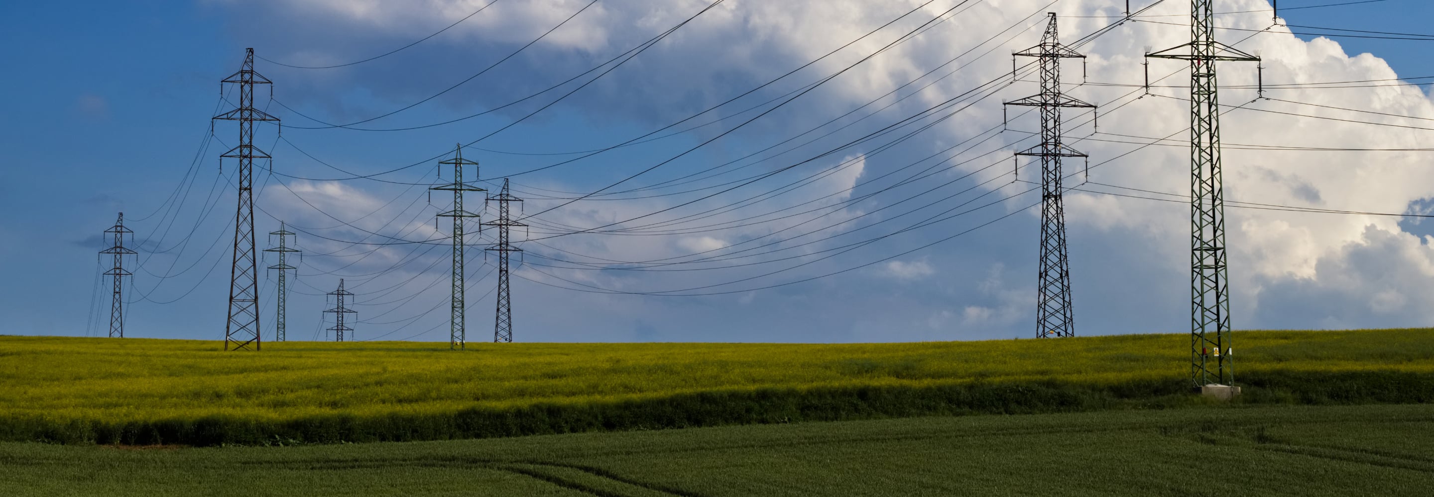 Electricity transmission towers and power lines over a green field