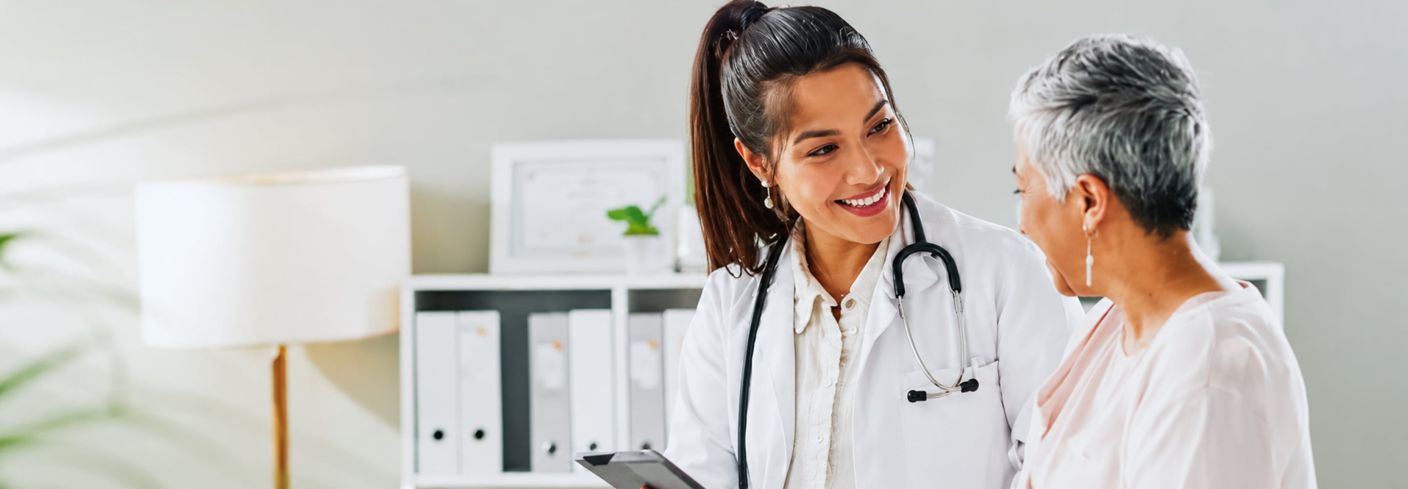Smiling doctor with a stethoscope talking with a senior patient