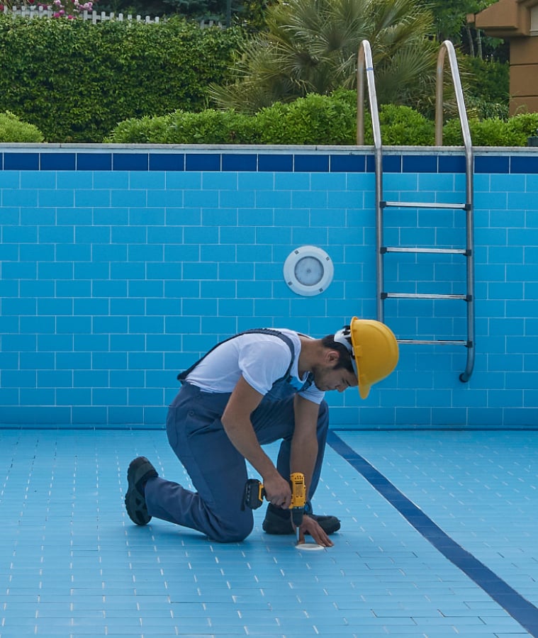 Empty residential pool being serviced, with blue tiled walls