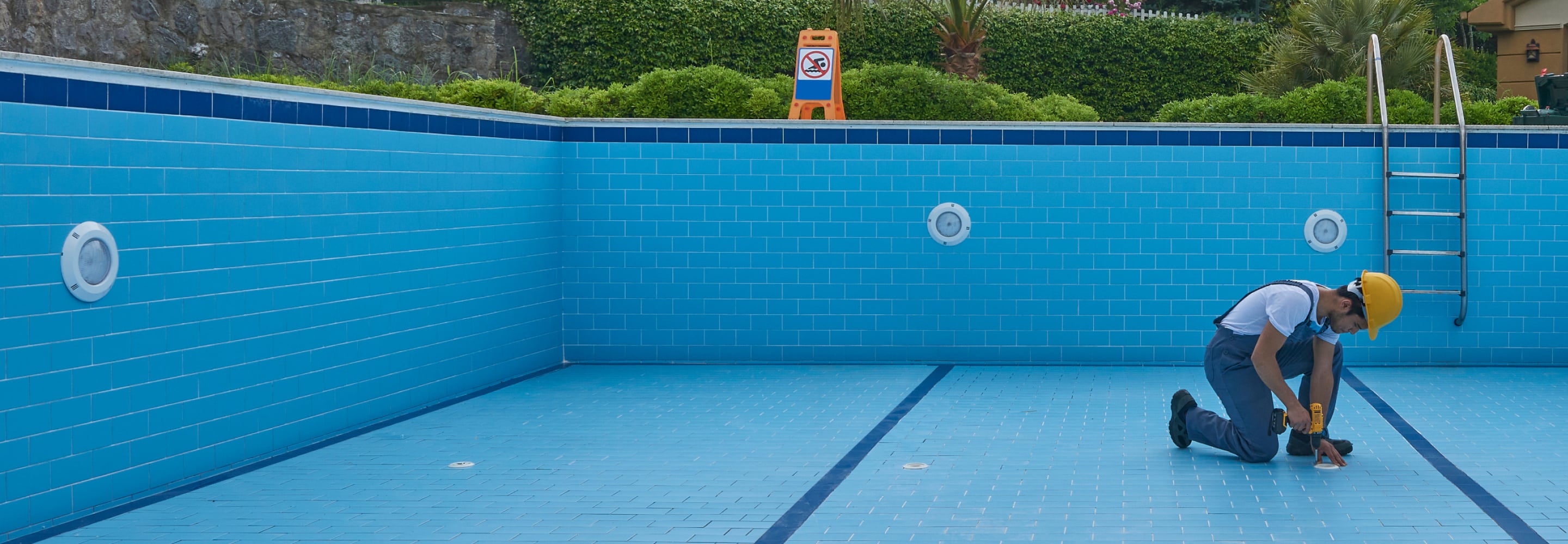 Empty residential pool being serviced, with blue tiled walls